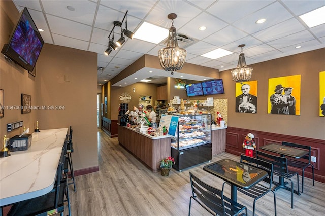 interior space with hanging light fixtures, light hardwood / wood-style floors, light stone counters, and a paneled ceiling