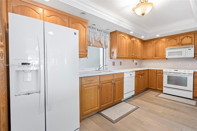 kitchen featuring light wood-type flooring, a raised ceiling, ornamental molding, sink, and white appliances