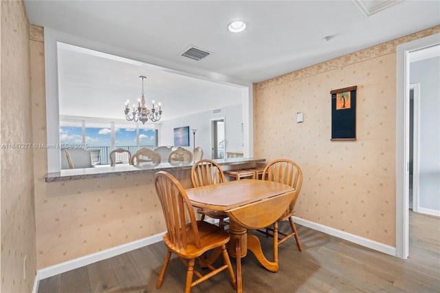 dining space featuring wallpapered walls, visible vents, a chandelier, and wood finished floors