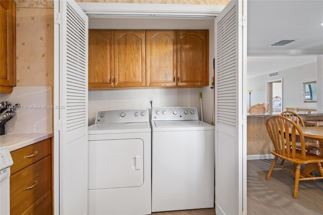 laundry area with independent washer and dryer, cabinet space, and visible vents