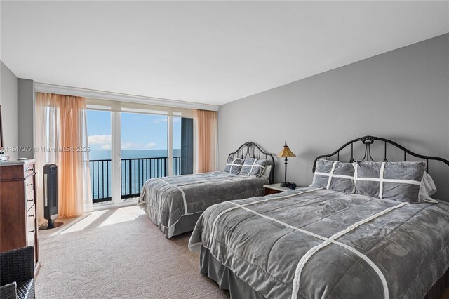 bedroom featuring access to outside, a water view, and light colored carpet