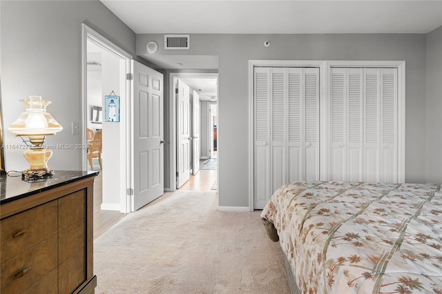 bedroom featuring two closets and light carpet