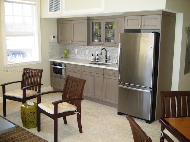 kitchen featuring backsplash, stainless steel appliances, light tile patterned floors, and sink