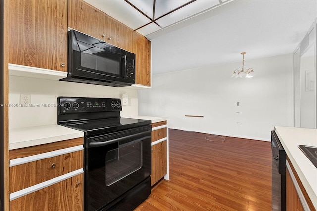 kitchen featuring light hardwood / wood-style floors, an inviting chandelier, black appliances, and hanging light fixtures