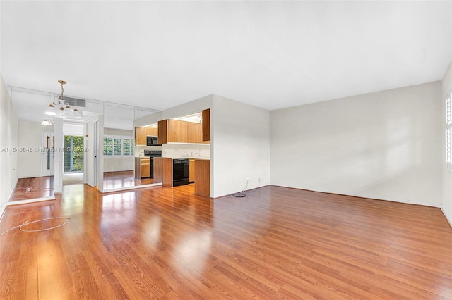 unfurnished living room with beverage cooler, light hardwood / wood-style flooring, and a chandelier