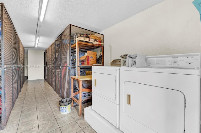 clothes washing area with light tile patterned floors, washing machine and clothes dryer, and a textured ceiling