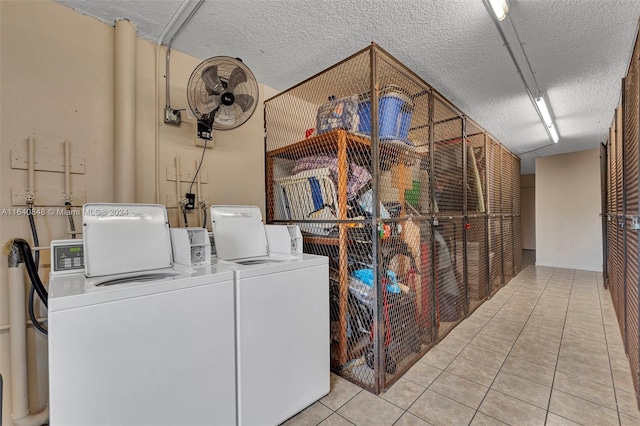 washroom featuring a textured ceiling, washer and clothes dryer, and light tile patterned floors