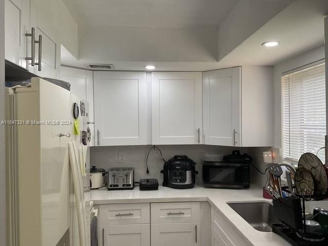 kitchen featuring white cabinets, a healthy amount of sunlight, and white fridge