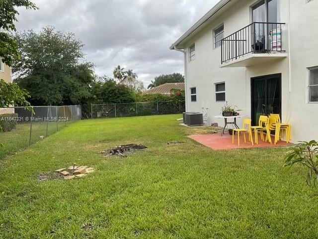 view of yard featuring a balcony, central air condition unit, and a patio