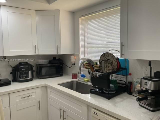 kitchen with white cabinetry, sink, and light stone counters