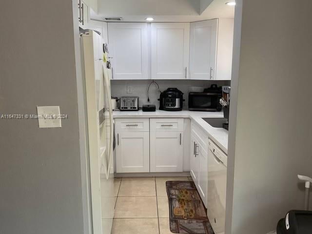 kitchen featuring tasteful backsplash, white cabinetry, white appliances, and light tile patterned floors