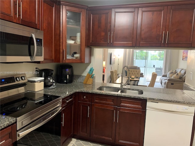 kitchen featuring kitchen peninsula, light stone counters, sink, and appliances with stainless steel finishes