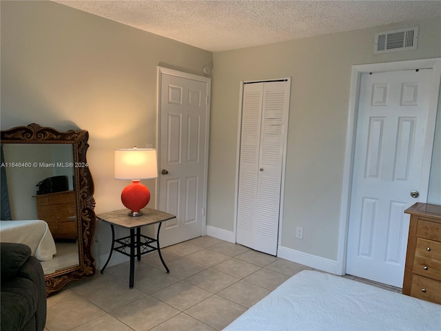 tiled bedroom featuring a textured ceiling and a closet