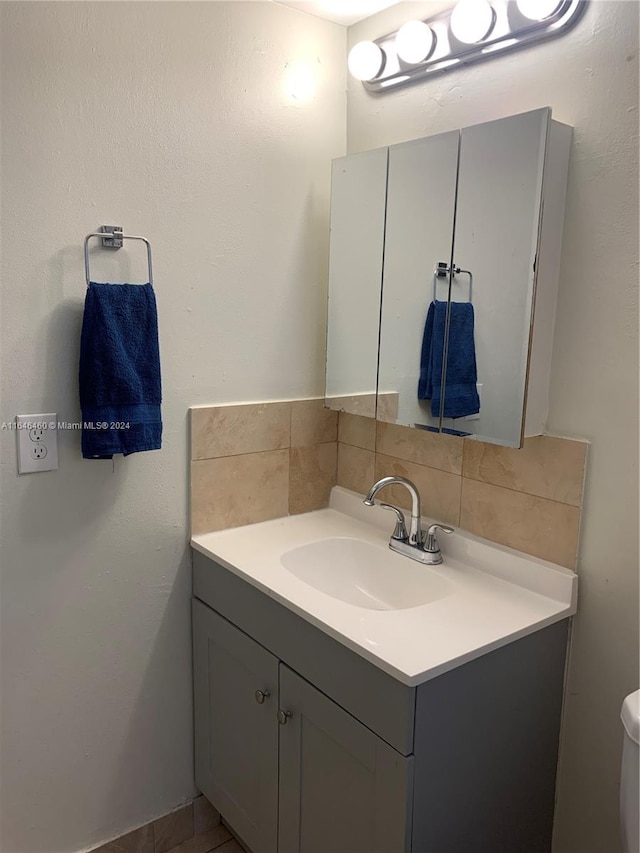 bathroom featuring vanity, toilet, and backsplash