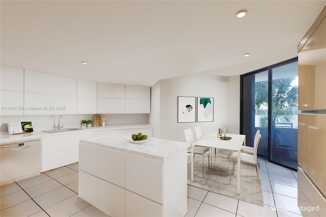 kitchen with dishwasher, a center island, light tile patterned flooring, sink, and white cabinetry