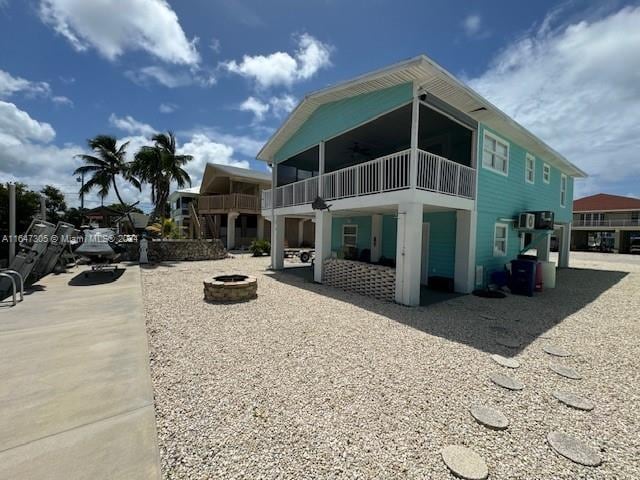 back of house with ceiling fan, a fire pit, a patio area, and a balcony