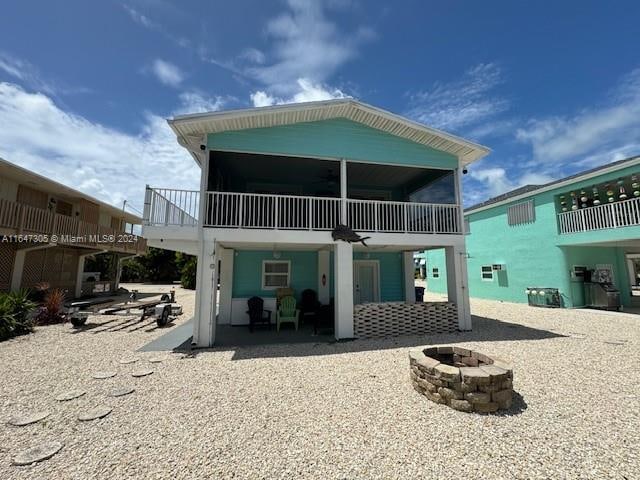 rear view of property with a balcony, an outdoor fire pit, ceiling fan, and a patio area