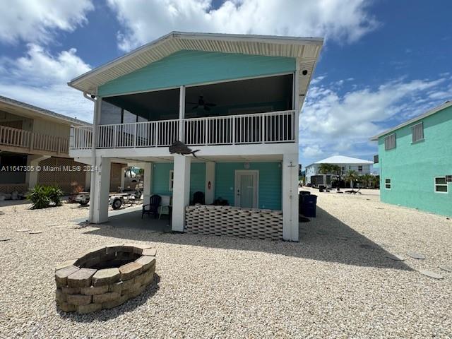 rear view of property with ceiling fan, an outdoor fire pit, a patio area, and a balcony