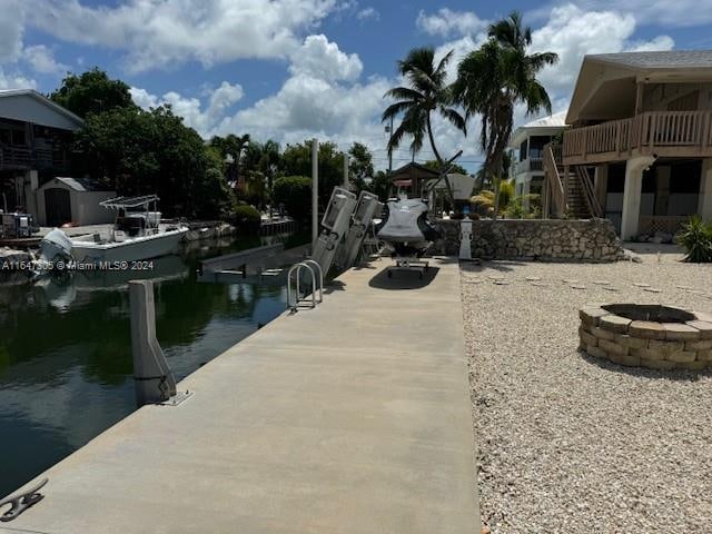 view of dock featuring a fire pit and a water view