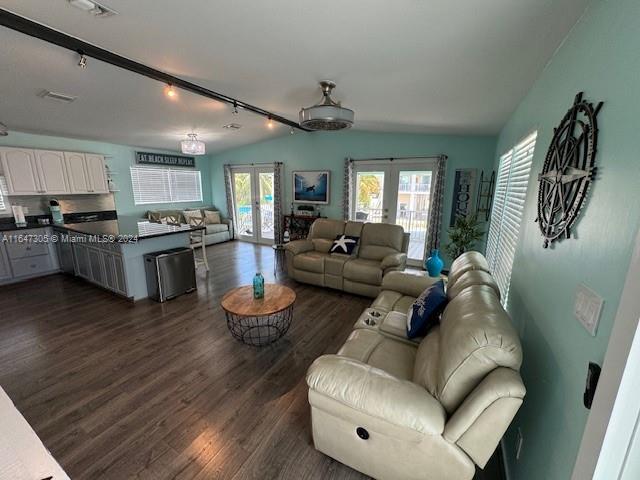 living room with rail lighting, dark hardwood / wood-style floors, vaulted ceiling, and french doors