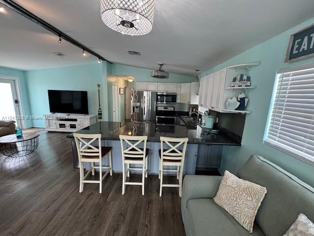 kitchen featuring a breakfast bar, dark hardwood / wood-style flooring, track lighting, stainless steel appliances, and kitchen peninsula