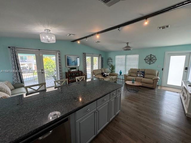 kitchen with dark stone counters, dark wood-type flooring, track lighting, french doors, and lofted ceiling