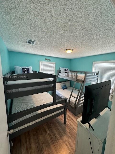 bedroom featuring wood-type flooring, a textured ceiling, and multiple windows