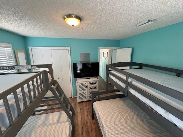 bedroom with hardwood / wood-style floors, a textured ceiling, and a closet