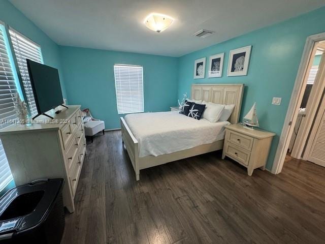 bedroom with dark hardwood / wood-style floors and multiple windows