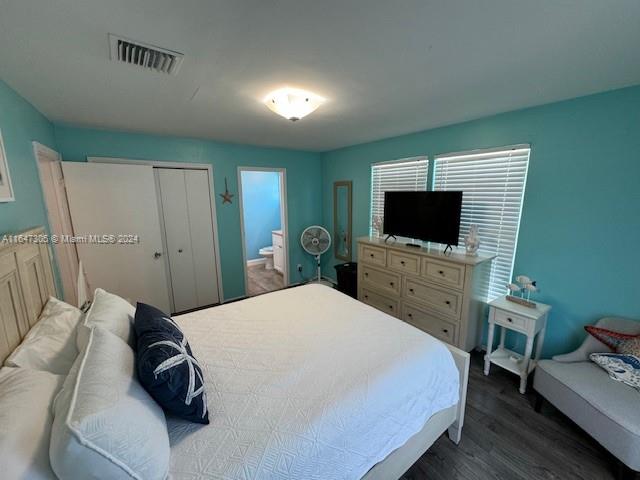 bedroom featuring a closet, dark hardwood / wood-style flooring, and ensuite bath