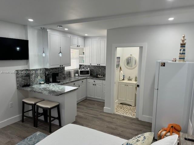 kitchen with white cabinetry, dark hardwood / wood-style floors, and white fridge