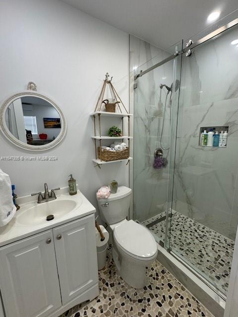 bathroom featuring tile patterned floors, an enclosed shower, vanity, and toilet