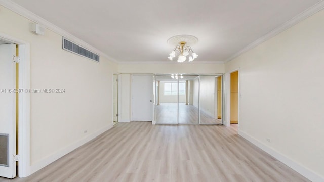 spare room featuring crown molding, a notable chandelier, and light wood-type flooring