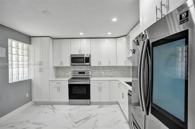 kitchen featuring appliances with stainless steel finishes, white cabinets, a wealth of natural light, and tasteful backsplash