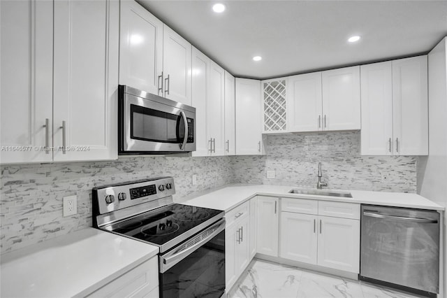 kitchen with stainless steel appliances, tasteful backsplash, sink, white cabinets, and light tile patterned flooring