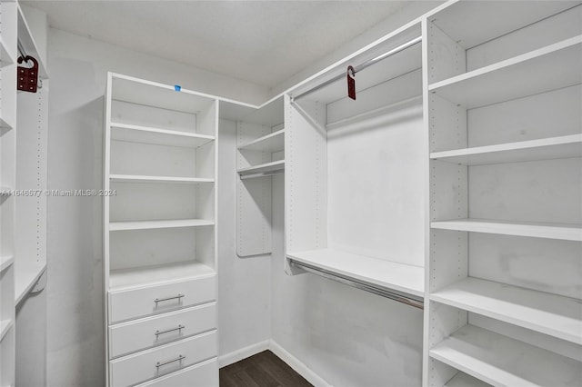 walk in closet with dark wood-type flooring