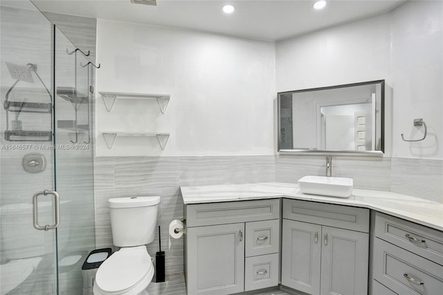 bathroom with tile walls, toilet, vanity, and walk in shower