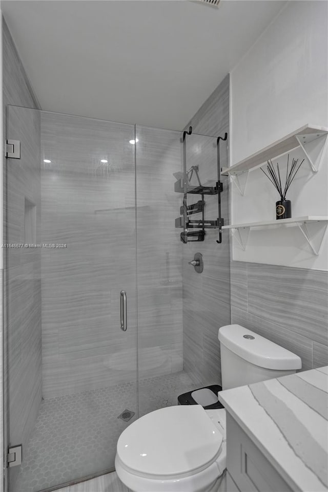 bathroom featuring tile walls, toilet, vanity, and walk in shower