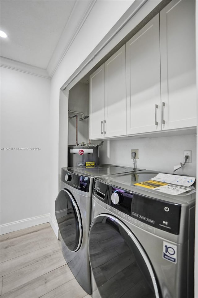 laundry room featuring light hardwood / wood-style floors, washer and dryer, ornamental molding, and cabinets