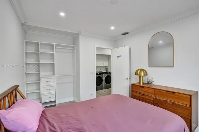 bedroom featuring a closet, crown molding, hardwood / wood-style floors, and washing machine and clothes dryer