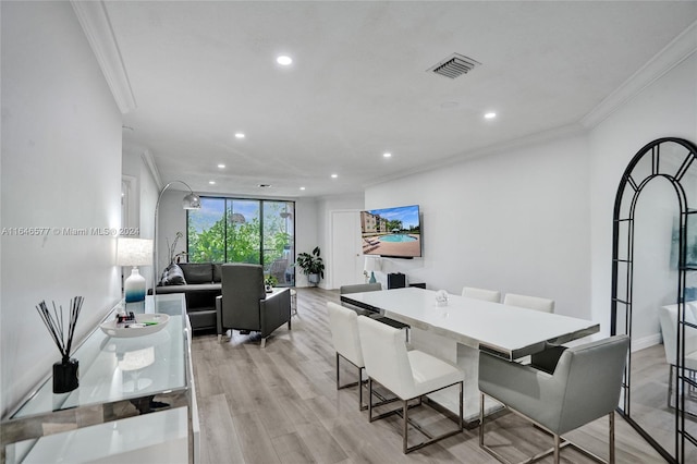 dining area featuring light wood-type flooring and crown molding