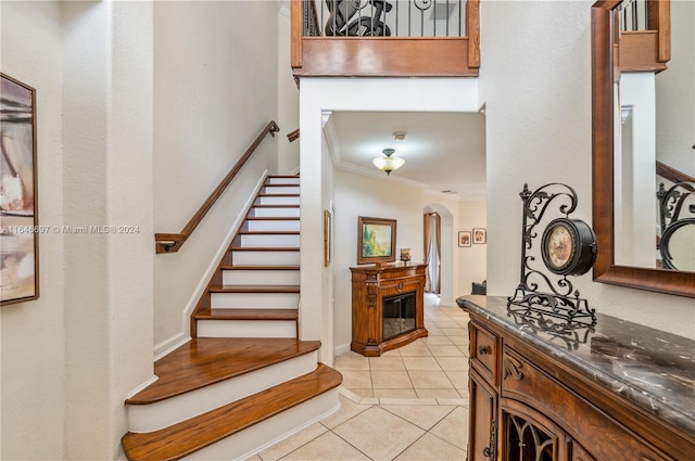 stairway with tile patterned flooring and ornamental molding