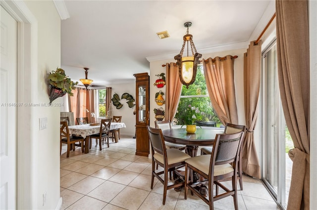 dining area featuring light tile patterned flooring, ornamental molding, and a healthy amount of sunlight