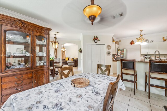 tiled dining space with ceiling fan and crown molding