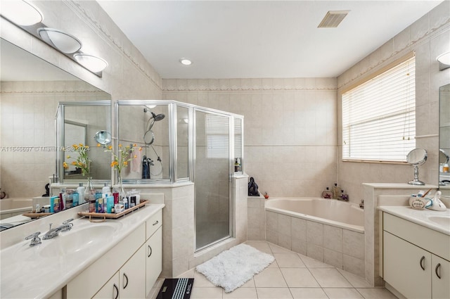 bathroom with plus walk in shower, tile walls, vanity, and tile patterned floors