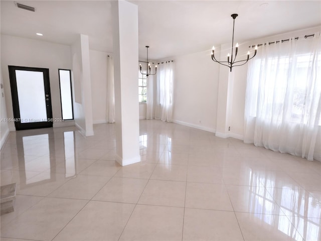 tiled empty room featuring a notable chandelier