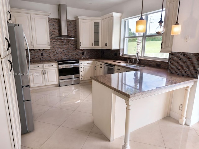 kitchen featuring sink, wall chimney exhaust hood, decorative backsplash, stainless steel appliances, and kitchen peninsula