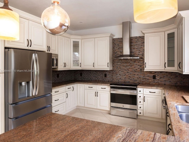 kitchen featuring light tile patterned flooring, backsplash, decorative light fixtures, stainless steel appliances, and wall chimney range hood