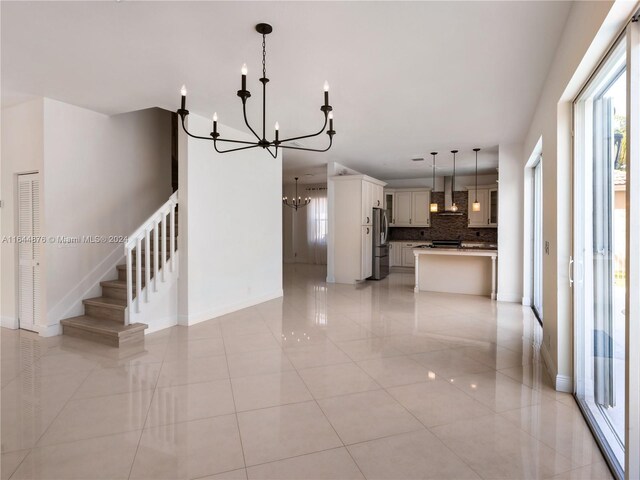 unfurnished living room featuring a notable chandelier and light tile patterned floors