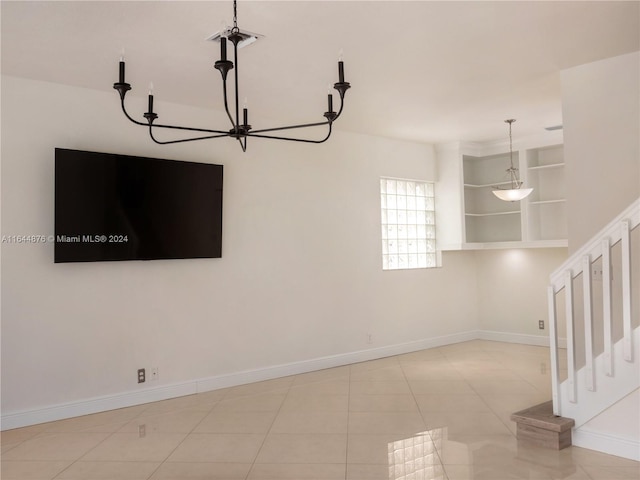 tiled spare room featuring an inviting chandelier and built in features